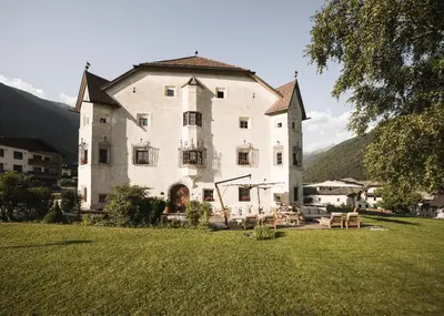 a large white building with a grass field in front of it at Ansitz Heufler by Norbert Niederkofler in Rasun di Sopra