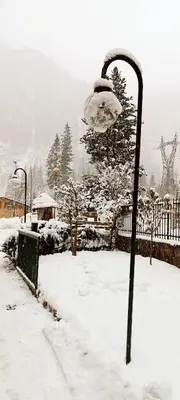 a street light covered in snow next to a fence at Pizzeria Marmolada Camere in Sottoguda