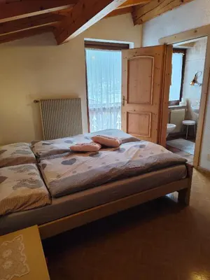 a bedroom with a bed with two pillows on it at Pizzeria Marmolada Camere in Sottoguda