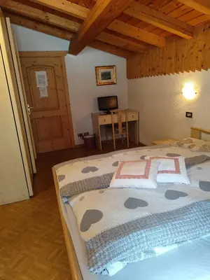 a bedroom with a large bed in a room at Pizzeria Marmolada Camere in Sottoguda