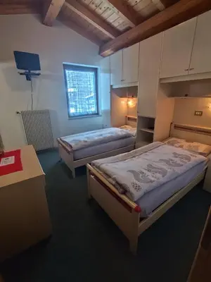 a bedroom with two beds and a window at Pizzeria Marmolada Camere in Sottoguda