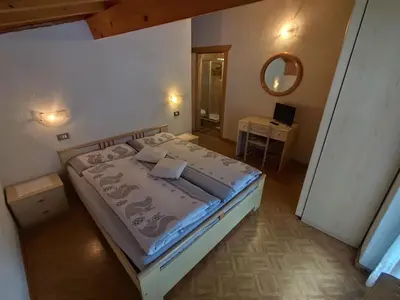a bedroom with a bed and a mirror on the wall at Pizzeria Marmolada Camere in Sottoguda