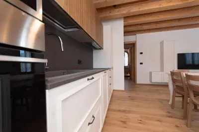 a kitchen with white cabinets and a stove top oven at Villa Caterina in Falcade