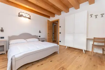 a bedroom with a white bed and a desk at Villa Caterina in Falcade