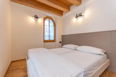 a bedroom with a large white bed with two pillows at Villa Caterina in Falcade