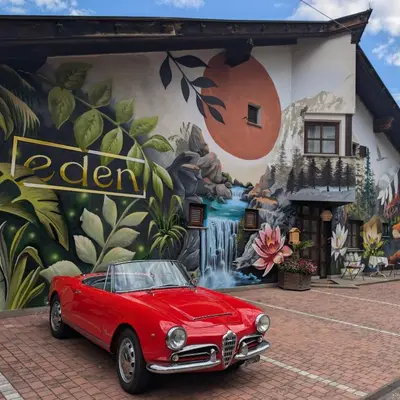 a red car parked in front of a mural at Hotel Eden Guesthouse in Marlengo