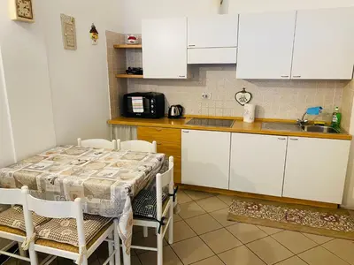 a kitchen with white cabinets and a table with chairs at Bilocale Cristina Mazzin in Campestrin