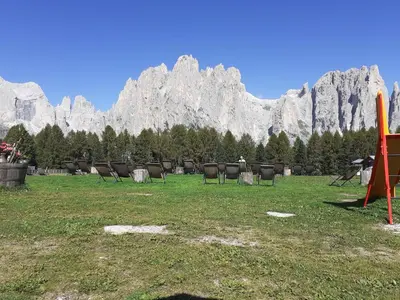 a group of chairs in a field in front of mountains at Bilocale Cristina Mazzin in Campestrin