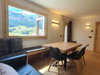 a dining room with a table and a large window at Casa Paolina - Alpine Stay Apartments in Tesero