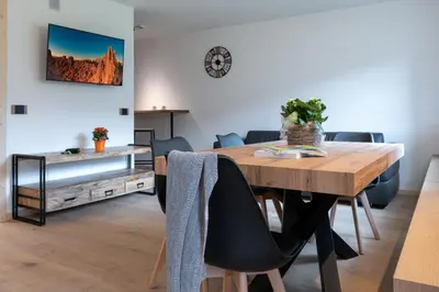 a dining room with a wooden table and chairs at Casa Paolina - Alpine Stay Apartments in Tesero