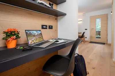 an office with a desk with a laptop and a chair at Casa Paolina - Alpine Stay Apartments in Tesero