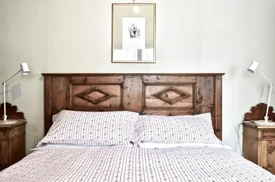 a bedroom with a bed with a wooden headboard and two lamps at Beautiful 3 bedroom flat in Cortina with car park in Cortina dʼAmpezzo