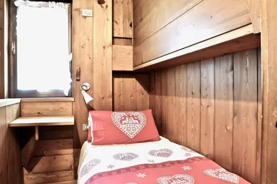 a bedroom with wooden walls and a bed with a red pillow at Beautiful 3 bedroom flat in Cortina with car park in Cortina dʼAmpezzo