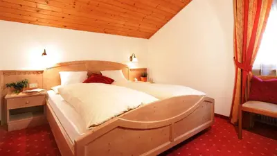 a bedroom with a large bed with a wooden headboard at Residence Carin in Selva di Val Gardena