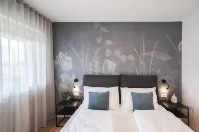 a bedroom with a white bed with a floral wall at LUXE VISTA City Apartments Algund in Lagundo