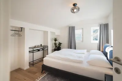 a bedroom with a white bed and a window at LUXE VISTA City Apartments Algund in Lagundo