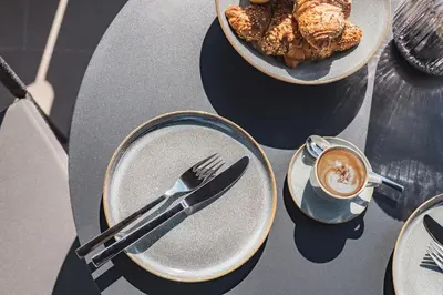a table with a plate of food and a cup of coffee at LUXE VISTA City Apartments Algund in Lagundo