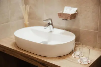 a bathroom with a sink and two glasses on a counter at Hotel Monte Cherz in Arabba
