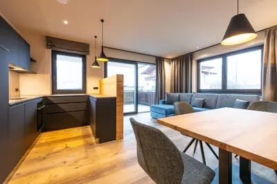 a kitchen and living room with a wooden table and chairs at Malojerhof in Lana