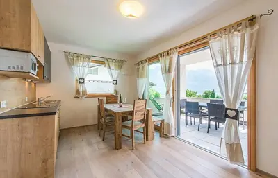 a kitchen with a table and chairs and a balcony at Sonngartenhof in Termeno