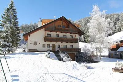 a house with snow on the ground in front of it at Planhof Apartments in San Martino in Badia