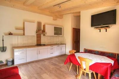 a kitchen with a table and a tv on the wall at Planhof Apartments in San Martino in Badia