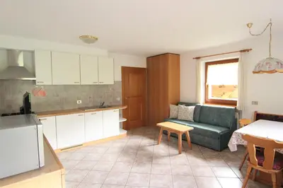 a kitchen and living room with a couch and a table at Planhof Apartments in San Martino in Badia