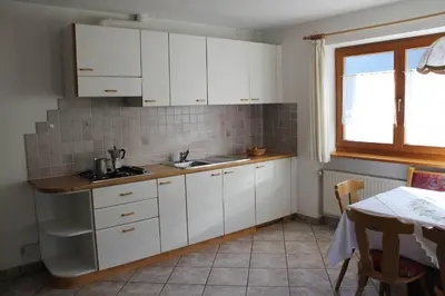a kitchen with white cabinets and a table and a window at Planhof Apartments in San Martino in Badia