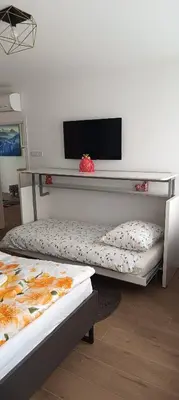 two beds in a room with a tv on a wall at Casa Giada in Bolzano