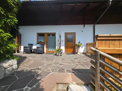 a stone patio with chairs and a wooden door at Apartments Insam in Santa Cristina in Val Gardena