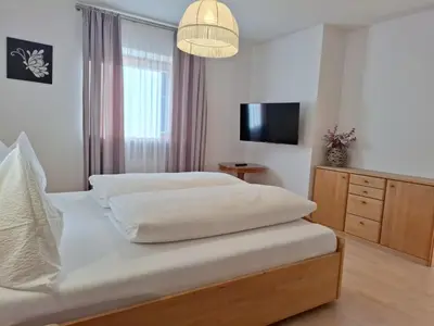 a bedroom with a bed and a chair at Apartments Insam in Santa Cristina in Val Gardena