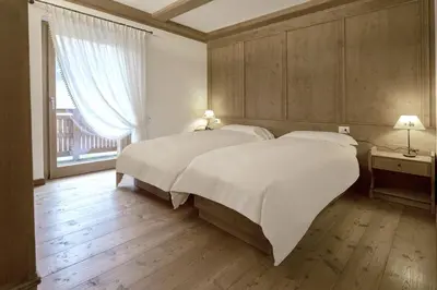 a bedroom with two beds with white sheets and a window at Ca' del Sole in San Vito di Cadore