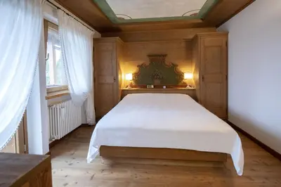 a bedroom with a white bed in a room with windows at Ca' del Sole in San Vito di Cadore