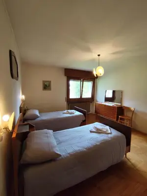 a room with three beds and a desk and a television at Panorama mozzafiato in Cortina dʼAmpezzo