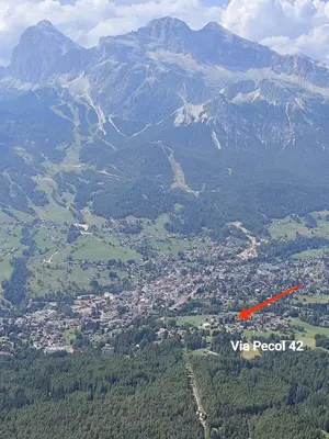 an airplane flying over a city with mountains in the background at Panorama mozzafiato in Cortina dʼAmpezzo