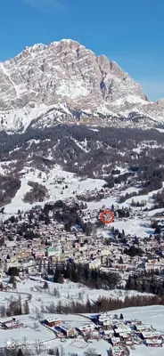 a town in the snow with a mountain in the background at Panorama mozzafiato in Cortina dʼAmpezzo
