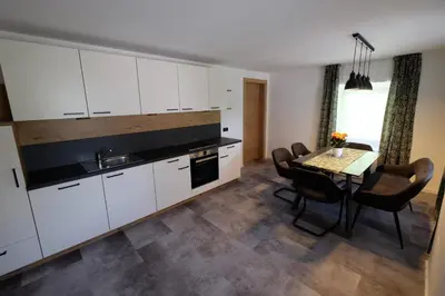 a kitchen with white cabinets and a table with chairs at Gasserhof in Campo di Trens