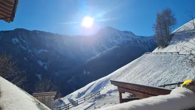 a snow covered roof with the sun shining on a mountain at Gasserhof in Campo di Trens