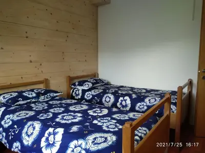 a bedroom with two beds with blue and white sheets at Maso de Propian in Tesero