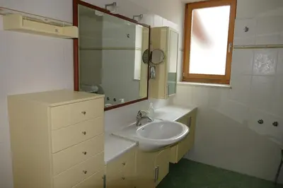 a white bathroom with a sink and a mirror at Maso de Propian in Tesero