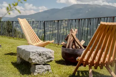 two rocking chairs and a fire pit in a yard at Proderhof in Feldthurns