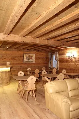 a living room with wooden ceilings and tables and a couch at Jägerhaus Agriturismo in Cortina dʼAmpezzo