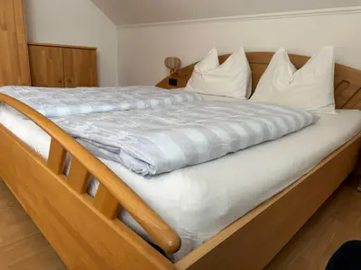 a wooden bed with white sheets and pillows at Appartments Anna in Valdaora di Sotto
