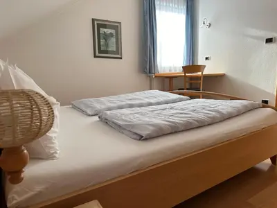 a bedroom with two beds and a chair at Appartments Anna in Valdaora di Sotto