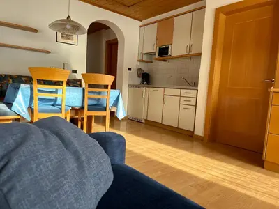 a living room with a blue couch and a kitchen at Appartments Anna in Valdaora di Sotto