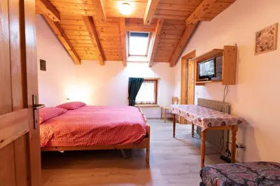a bedroom with a bed and a table in a room at Agritur Iellici in Castello di Fiemme
