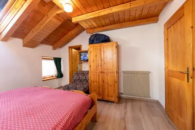 a bedroom with a bed and a wooden ceiling at Agritur Iellici in Castello di Fiemme