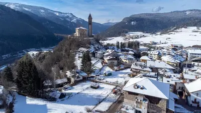 an aerial view of a village in the snow with a clock tower at Agritur Iellici in Castello di Fiemme