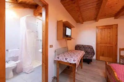 a bathroom with a table and a chair and a tub at Agritur Iellici in Castello di Fiemme