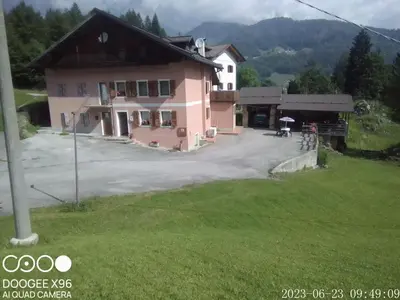 a house in the mountains with a green lawn at B&B SòT AL PIZ in Sagron Mis